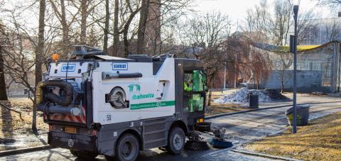A brush tractor cleans the pavement in Kirjastonpuisto Park.