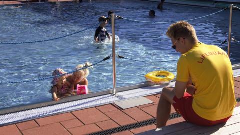 Uima-altaassa pieniä lapsia uimassa ja uimavalvoja 