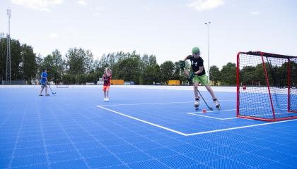 Blue floorball box outdoors and three children playing.