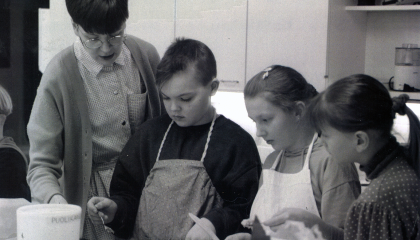 Opettaja leipoo kolmen lapsen kanssa.