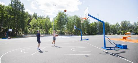 Kaksi nuorta pelaa koripalloa Kalevan urheilupuistossa.