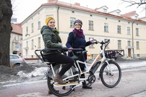 Elina Seppänen stands next to a bike and Emmi Nieminen sits on the bike rack.