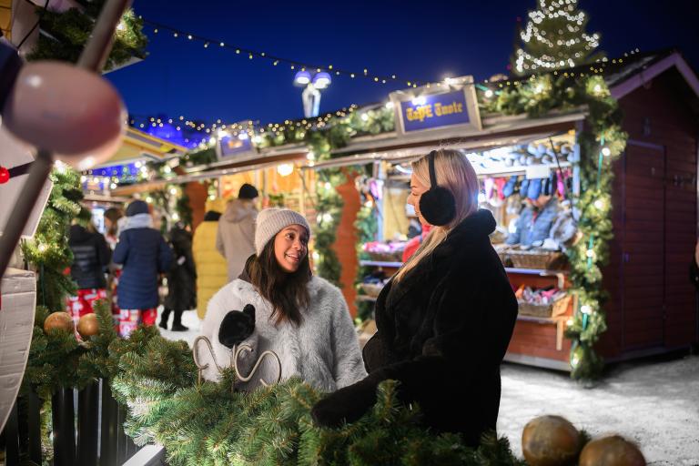 Kaksi henkilöä nauttimassa Joulutorin tunnelmasta pimeään aikaan.