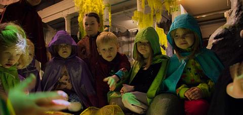 Lapset istuvat vihreän leikkilammen ympärillä.