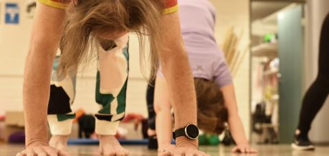 Kaksi henkilöä jooga-asanoissa liikuntasalissa.