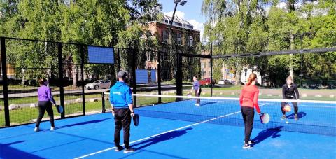 Young people play padel with a sports instructor.