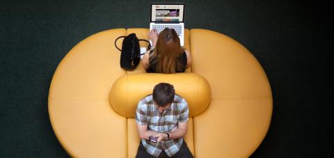 The top view shows two people sitting and using a laptop and a smartphone.