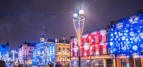 People looking at Christmas lights and the Finnish flag at Keskustori Central square.