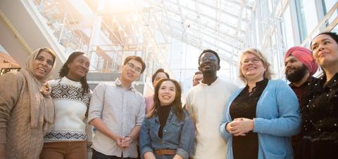Eight Tampere residents from different cultural backgrounds stand side by side.