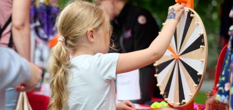 A child spinning a wheel of fortune at a Puistofiesta event.