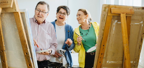 Three people are standing next to their easels.