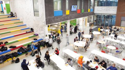 Kuva Tesoman koulun aulasta, jossa oppilaat ovat ruokailemassa.