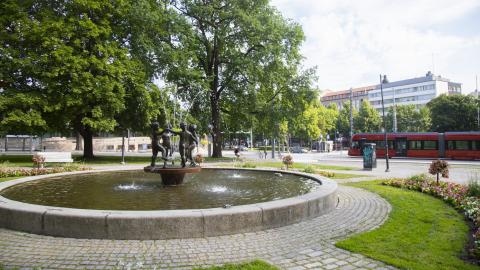 A fountain in Pyynikki Church Park, with a tram in the background.