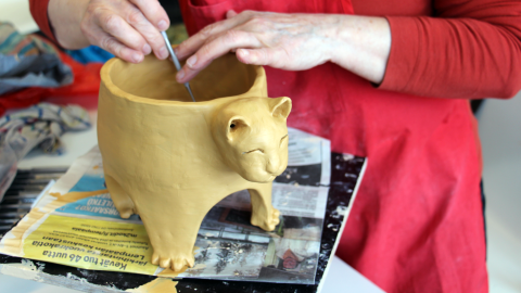 Henkilön kädet, jotka viimeistelevät keramiikkatyötä.