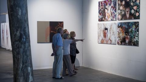 Neljä ihmistä katsoo museon seinällä olevia taideteoksia.