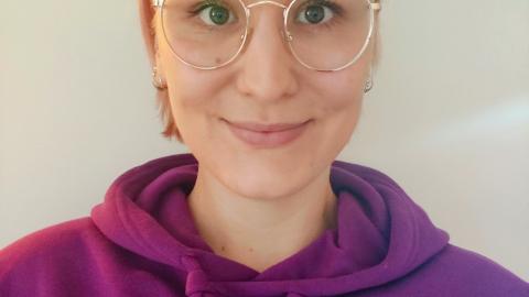 Kuvassa on Noora. Nooralla on silmälasit ja violetti huppari.