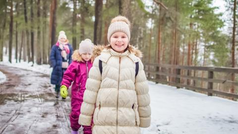 Kaksi lasta ja yksi aikuinen kävelevät peräkkäin talvisella Pyynikillä.