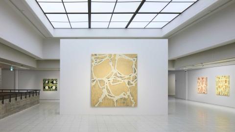 Näkymä Jukka Mäkelän näyttelyn aulasta, jossa väliseinälla suuri maalaus, takaseinällä yksi maalaus, ja oikealla sivuseinällä kaksi maalausta. 