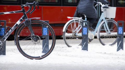 Pysäköityjä polkupyöriä lumisella kadulla
