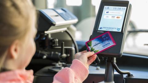 Tyttö käyttää matkakortin bussin lukijalaitteessa.