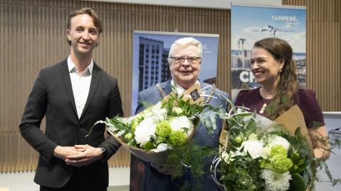 Kalervo Kummola ja Anna-Kaisa Ikonen saivat kukkakimput käteensä ja Ilmari Nurmio hymyilee vieressä.