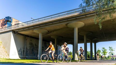 Kolme pyöräilijää Ratinan sillan alta kulkevalla pyörätiellä.