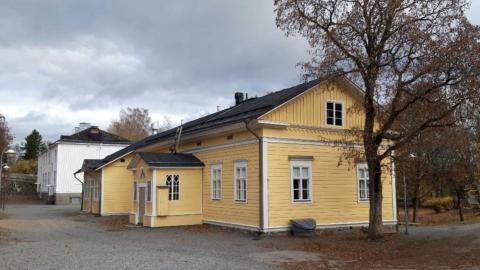 Harjun koulun keltainen koulurakennus etualalla, taustalla valkoinen koulurakennus ja pihapiiriä.