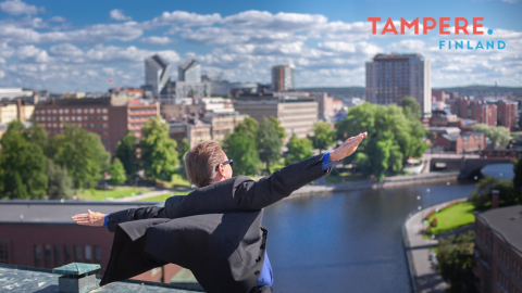 Mies katsoo katolta Tampereen kaupunkinäkymää kädet levällään.