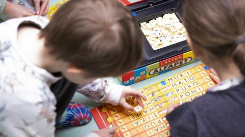 Lapsia leikkimässä sanaristikkolautapeliä.