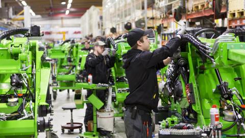 Nuoret työntekijät asentavat koneita teollisuushallissa.