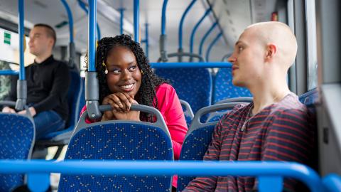 Tyttö ja poika juttelevat bussissa.