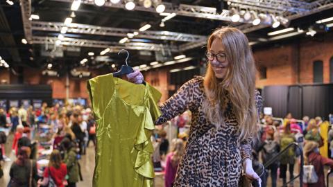 A woman shows off a dress at a clothes exchange event.
