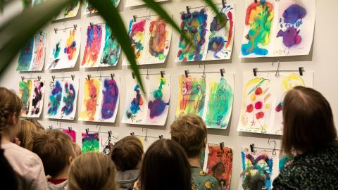 Lapsiryhmä katsoo värikkäitä taideteoksia.