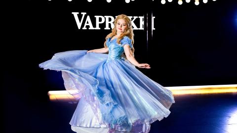 Vaaleahiuksinen tyttö sinisessä leveähelmaisessa mekossa pyörähtämässä Vapriikin aulassa.