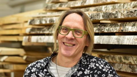 Henkilö seisoo puumateriaalien edessä puukäsityöluokassa.