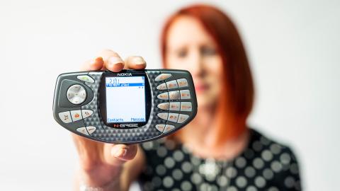 Nokian N-Gage -pelikonsolia pitää kädessä punahiuksinen nainen.