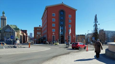 Auto ja kävelijä Lapintien kiertoliittymässä, hotelli Tammer ja paloasema taustalla.