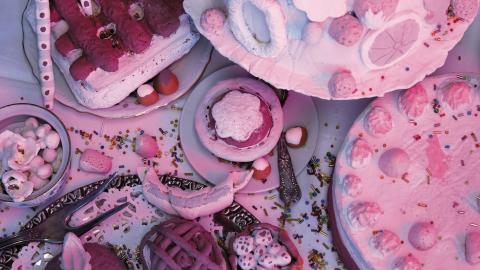 Installaatiossa on vaalenanpunaisia herkkuja kuten kakkuja ja leivoksia.