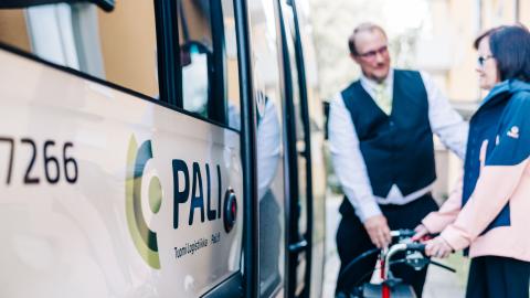 Palveluliikenteen avustaja auttaa rollaattoria käyttävää siirtymään Pali-bussin kyytiin.