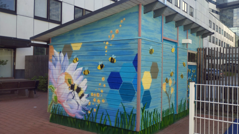 Laudoista tehty vaja, jonka seinillä kukka- ja hyönteisaiheisia maalauksia.