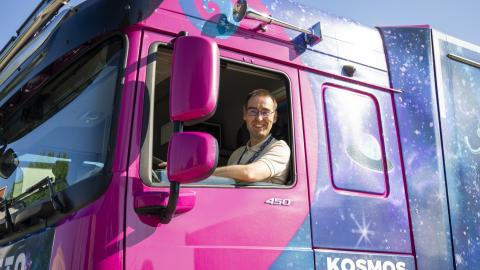 Kuljettaja katsoo purppuran värisen kuorma-auton ikkunasta.