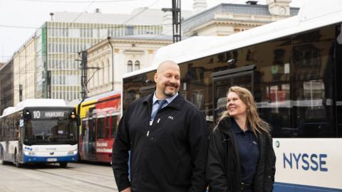Kaksi bussikuskia seisoo jalkakäytävällä Hämeenkadulla kulkevan Nysse-bussin edessä.