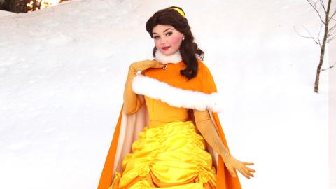 Prinsessa keltaisessa juhlamekossa ja karvaviitassa, kuvattu talvisessa maisemassa.