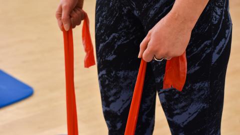 Henkilö pitää kiinni jumppakuminauhasta ja vetää sitä lattialta.