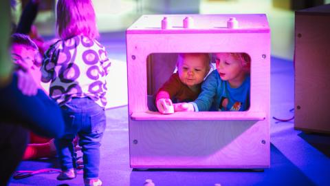 Kolme taaperoa leikkimässä näyttelyssä. 