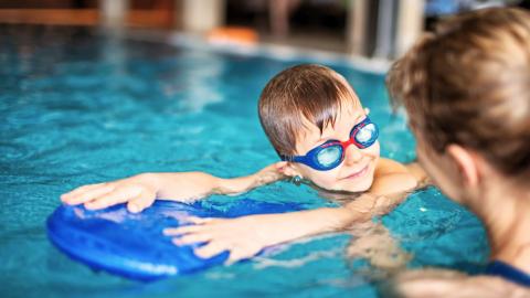 Pieni poika harjoittelee uimista uimalaudan avulla.