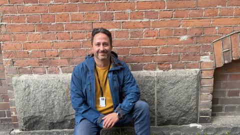 Klaus smiles directly at the camera while kneeling.