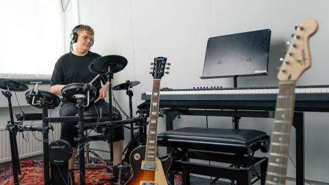 Henkilö soittaa sähkörumpuja, edustalla muitakin soittimia.