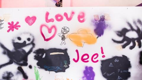 Happy looking characters, hearts, the sun and the words &quot;Love&quot; and &quot;Yay&quot; on a graffiti wall.