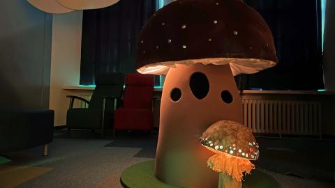 Iso ja pieni käsin tehty sieni, joiden hatut hohtavat valoa. 